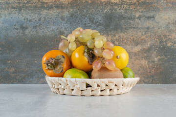 A wicker basket full of sweet fruits on white background