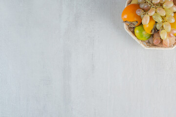 A wicker basket full of sweet fruits on white background