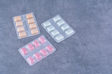 Assorted aluminium foil packs of gum on marble background