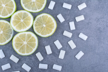 Lemon slices and chewing gum scattered over marble background