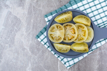 Fermented tomato slices on dark board with tablecloth