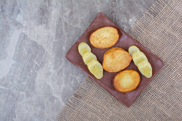 Fried potato slices and pickled cucumbers on plate
