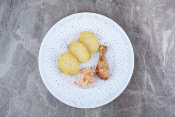 Grilled chicken leg, potato and sauerkraut on white plate