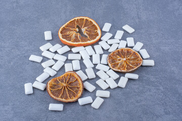 Dried orange slices and a bunch of gummy tablets on marble background