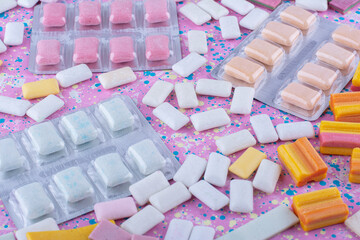Gum tablet packs amid scattered bubblegum pieces on a colorful background