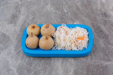 Sauerkraut and pickled fruits on blue plate