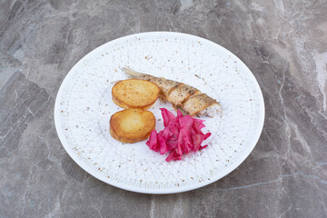 Herring rolls, potato and red cabbage on white plate