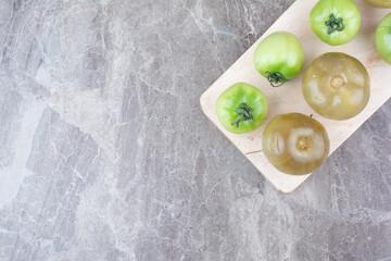 Fresh green tomatoes and pickled tomatoes on wooden board