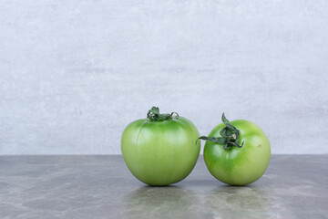 Two green tomatoes on marble background
