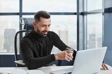 Fototapeta premium tired businessman drinks coffee sitting at his desk.