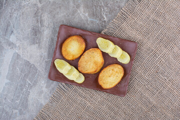 Fried potato slices and pickled cucumbers on plate