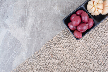 Two bowls of pickled garlic and plums on burlap