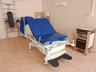 Maternity room with a gynecological gurney for childbirth, wall bars and medical equipment to...
