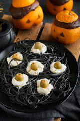 Halloween party jack-o-lantern chocolate orange cakes against the background of the old forest, branches and leaves. Halloween food concept. Sweets for Halloween celebration.