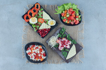 A variety of salads on platters displayed on marble background