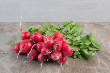 Red turnips and turnip leaves on marble background
