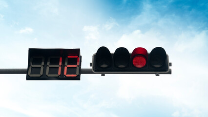 Red traffic light. with the countdown number twelve. Background of blue sky and white clouds.