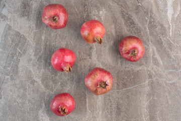 Six pomegranates neatly aligned on marble background
