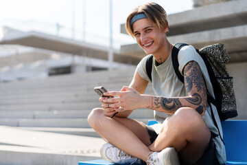 Short hair woman with dental braces sitting in the street in the city and using her mobile phone.