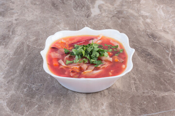 Borsch soup with coriander garnish on marble background