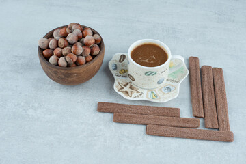 A cup of coffee with various nuts and cookies