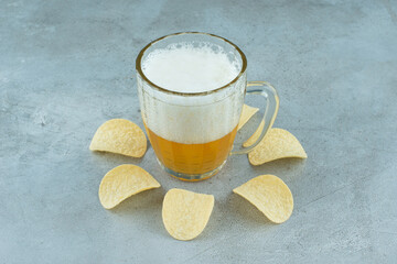 A glass of light delicious beer with potato chips