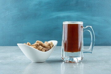 A big glass of beer with white plate full of cashew