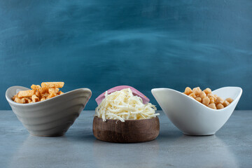 Three colorful plates of delicious snacks with wooden bowl full of cheese