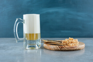 A glass of beer with wooden plate of fish and peas