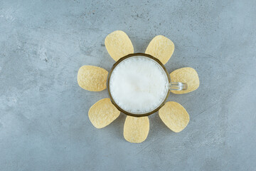 A glass of light delicious beer with potato chips