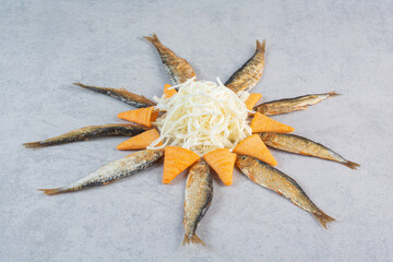 Fish with cheese and yellow chips on gray background
