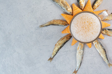 A glass of beer with fish and yellow crispy chips