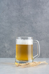 A glass of delicious beer with wheat on hay background