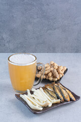 A dark plate full of delicious fish and cheese with beer and peas
