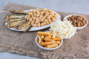 A white plates full of fish and breadsticks on sackcloth background