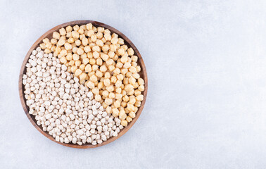 Cooked and raw chickpeas heaped on a large tray on marble background