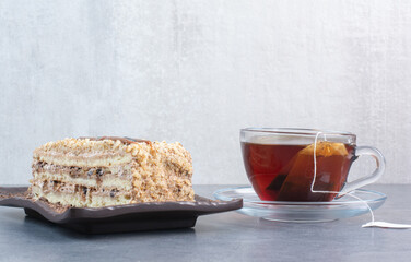 A piece of cake with cup of aroma coffee on gray background