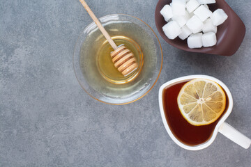 Obraz na płótnie Canvas A cup of tea wit sugar and honey on gray background
