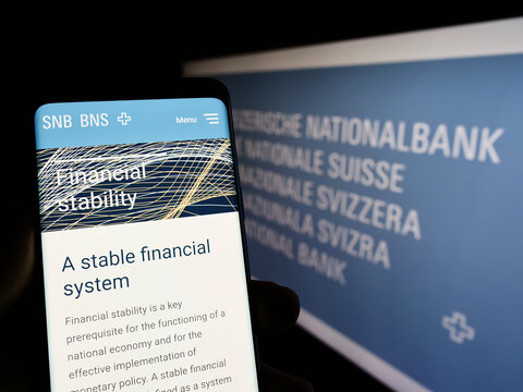 Stuttgart, Germany - 09-26-2022: Person holding cellphone with web page of financial institution Swiss National Bank (SNB) on screen with logo. Focus on center of phone display.