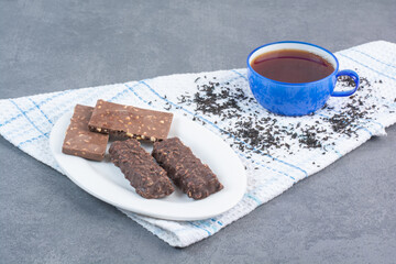 Sweet chocolates with cup of tea on tablecloth