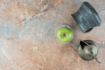 A fresh apple with an ancient cups on marble background