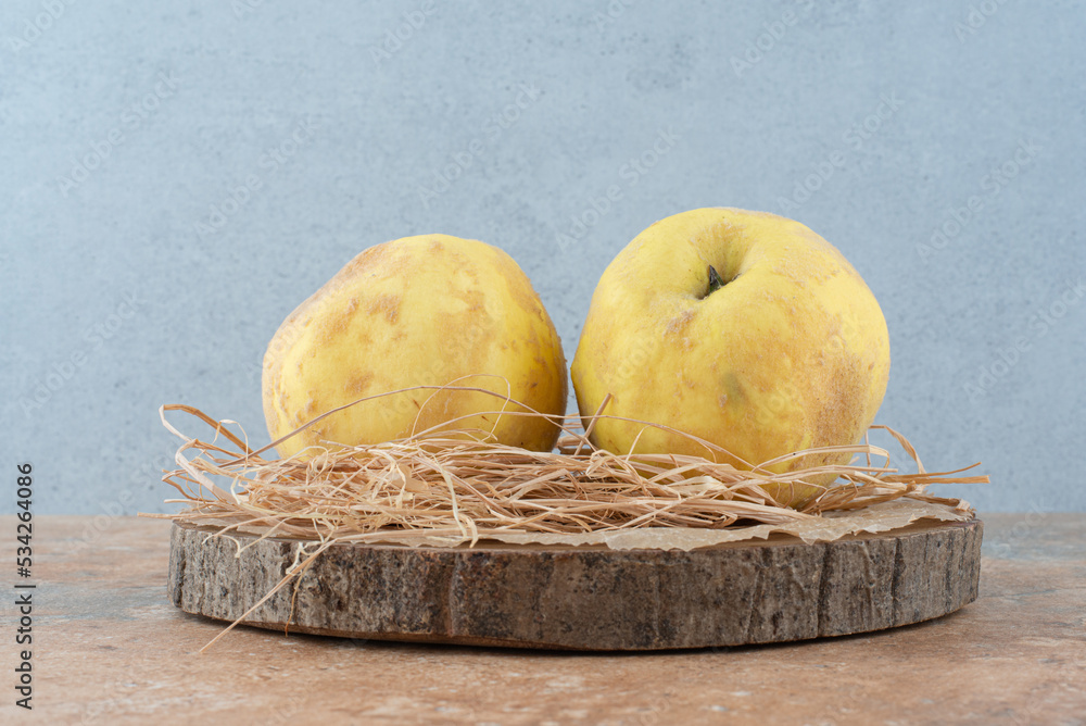 Wall mural two fresh quinces on wooden board with hay