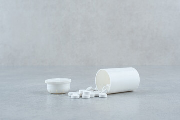 White jar of medicines on gray background