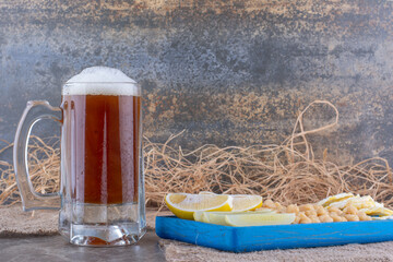 Plate of snacks and glass of beer on marble surface