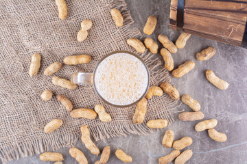 Glass of beer and scattered peanuts on marble table