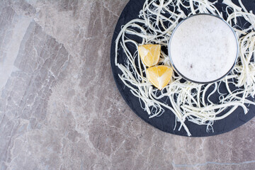 Glass of beer with cheese and lemons on dark board