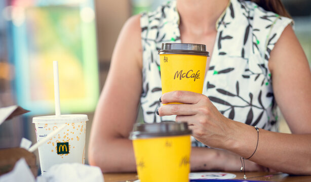 McDonald's in Poland - Nowy Sacz - August 18, 2022. Young woman holds a cup of delicious coffee from mcdonalds restaurant in her hand. Shallow depth of field.