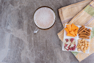 Plate of variety of snack and beer on marble surface