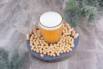 Glass of beer, peas and peanuts on wooden piece
