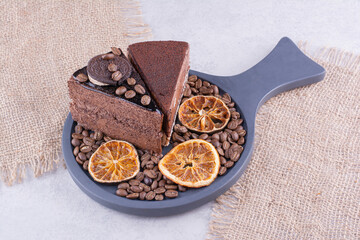 Two slices of chocolate cakes with coffee beans and orange slices